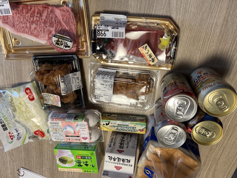 Japanese convenience store haul spread on a hotel room floor