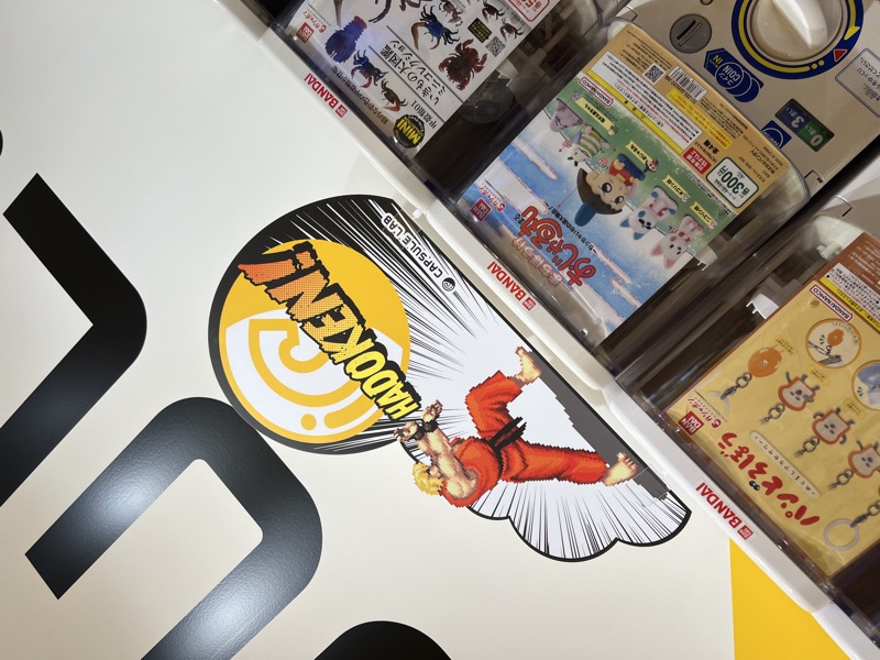 Capsule Lab gacha wall showing Street Fighter Zangief alongside rows of Bandai series capsule machines