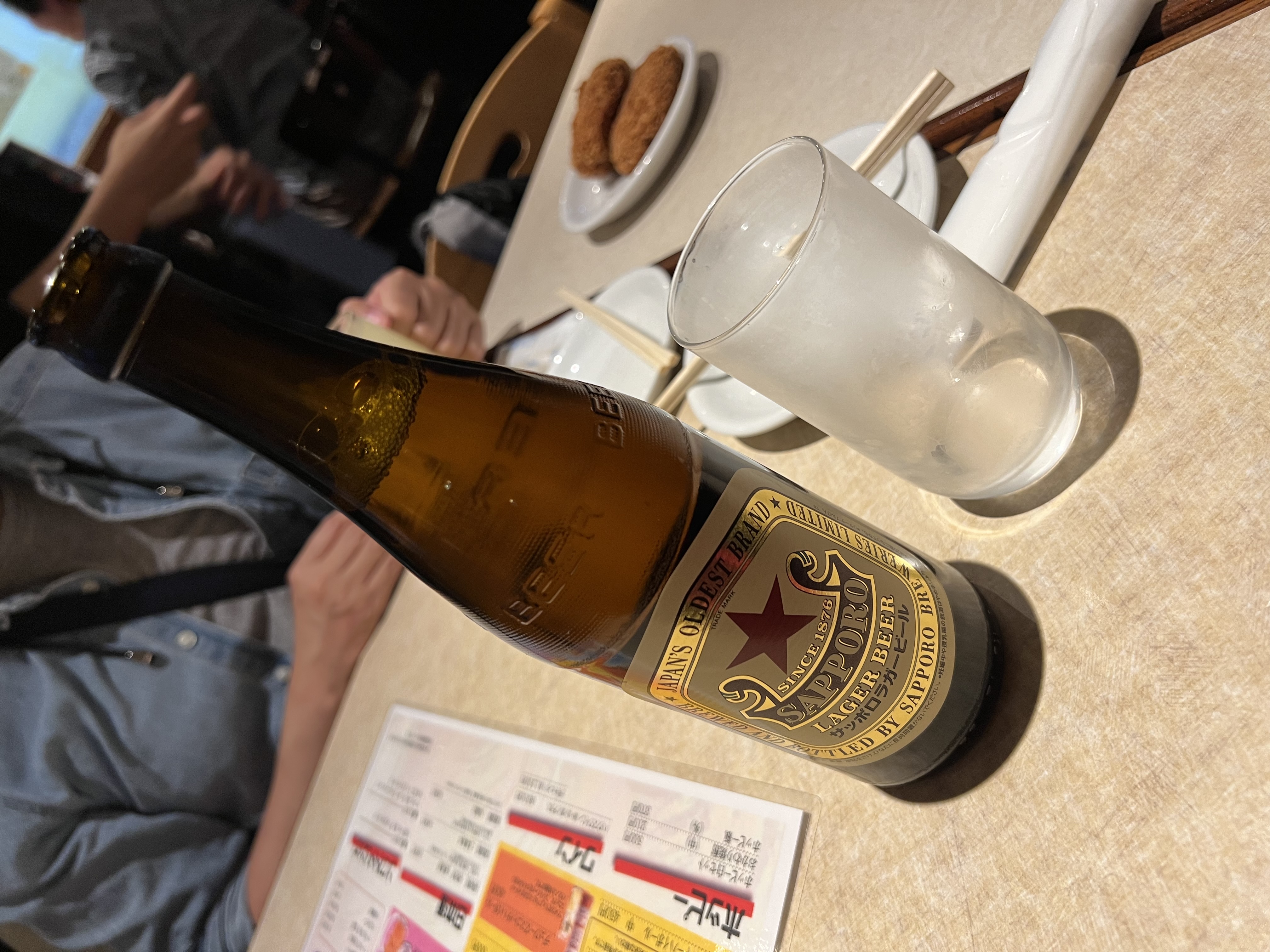 Sapporo beer bottle on the table at Ohyama, menu spread out underneath