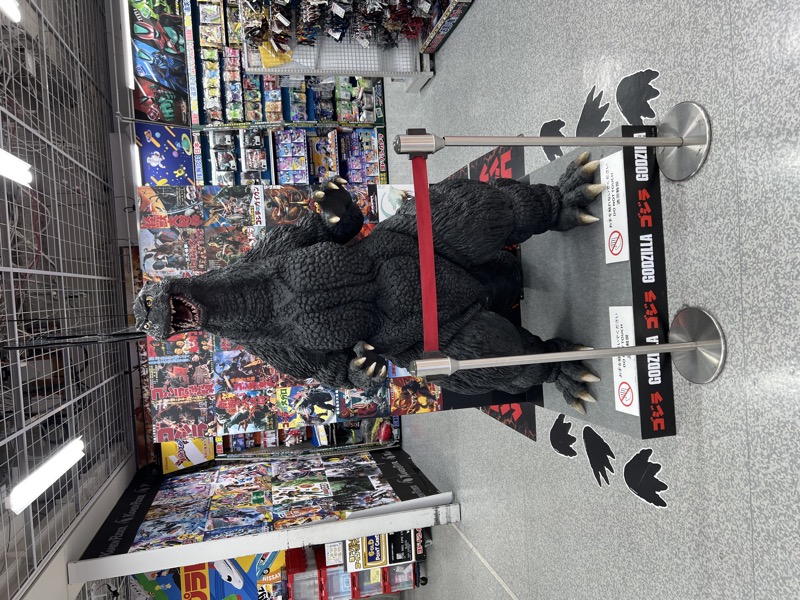 Life-size Godzilla figure standing in the middle of a collectibles shop