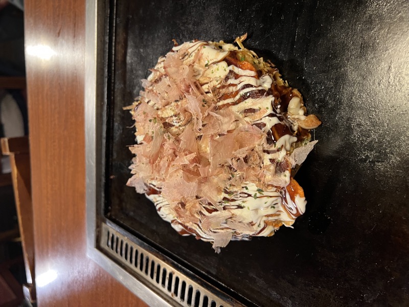 Okonomiyaki on a cast iron teppan with dancing bonito flakes