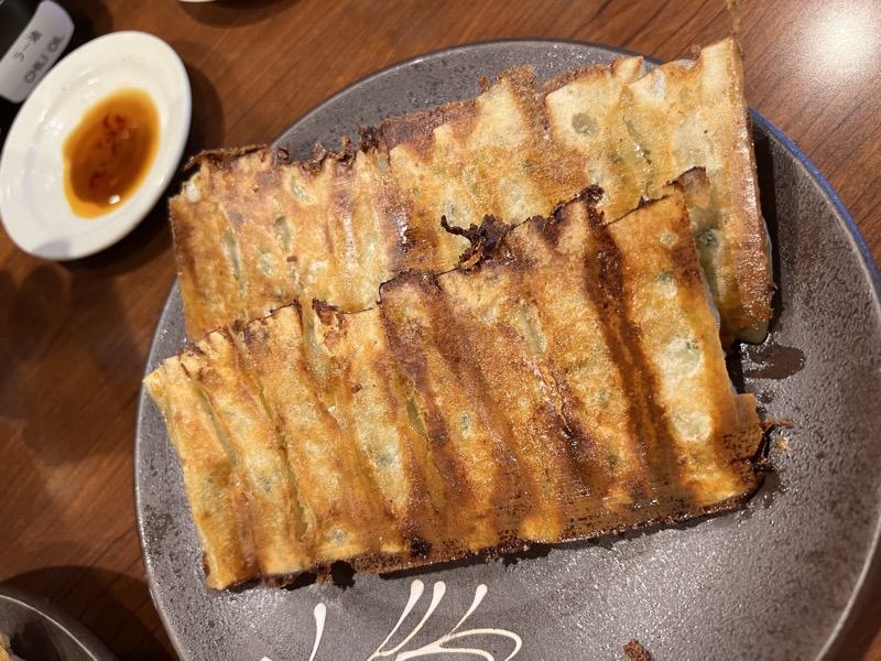 Pan-fried gyoza, deeply charred on the bottom, on a grey ceramic plate